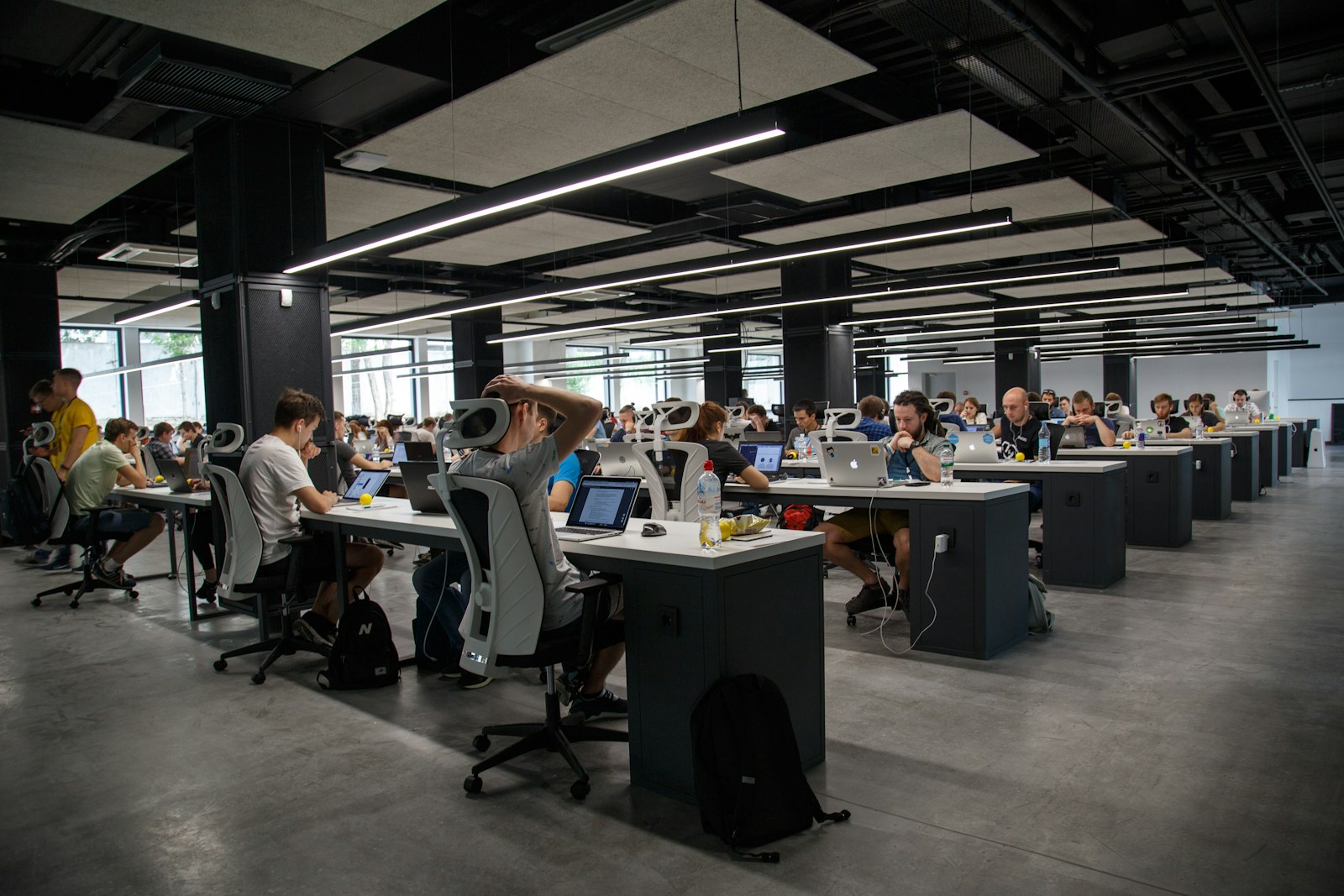 Equipo trabajando concentrado en oficina abierta con techo industrial.