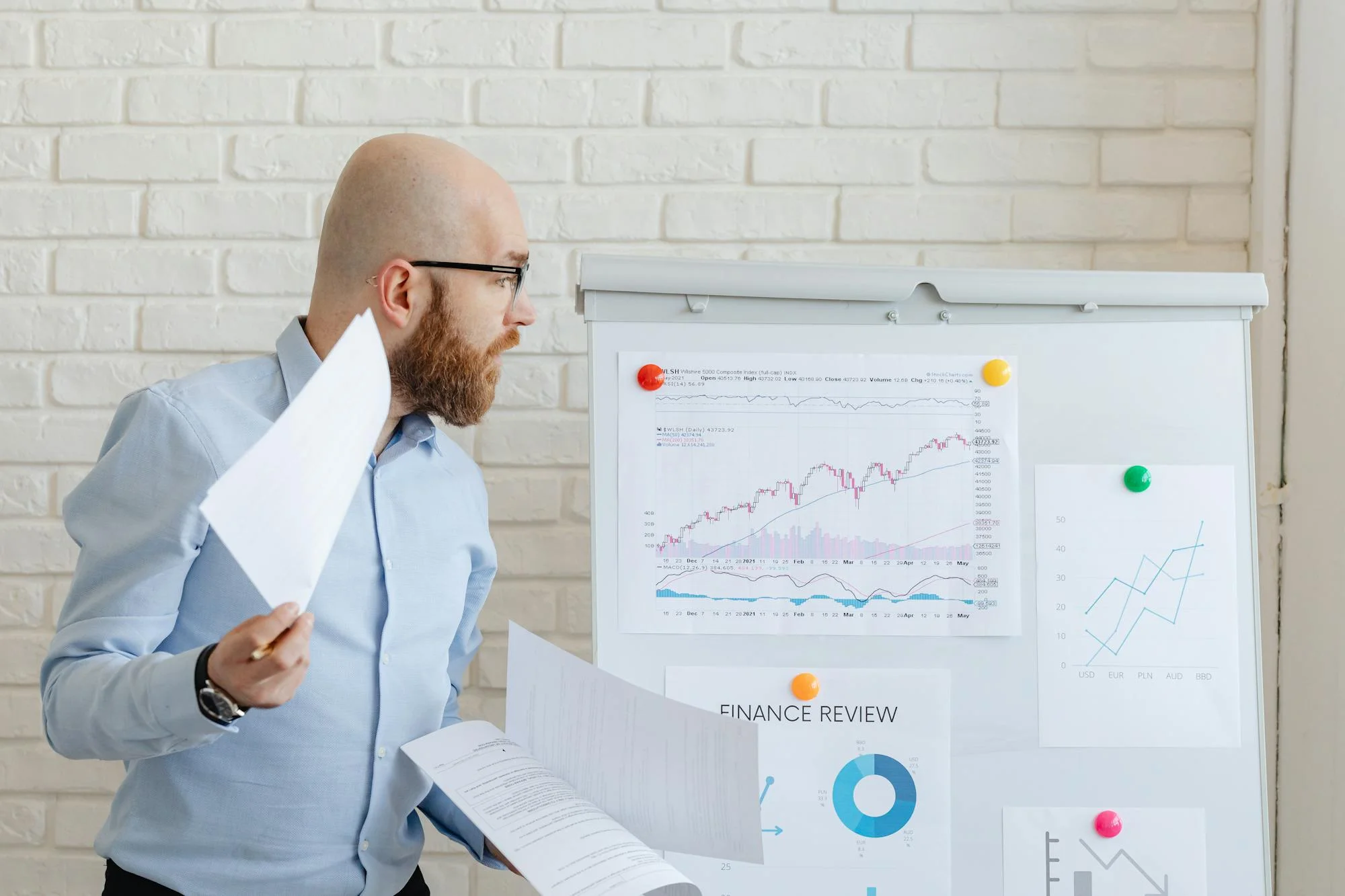 Persona analizando gráficos y datos en una pizarra de oficina.